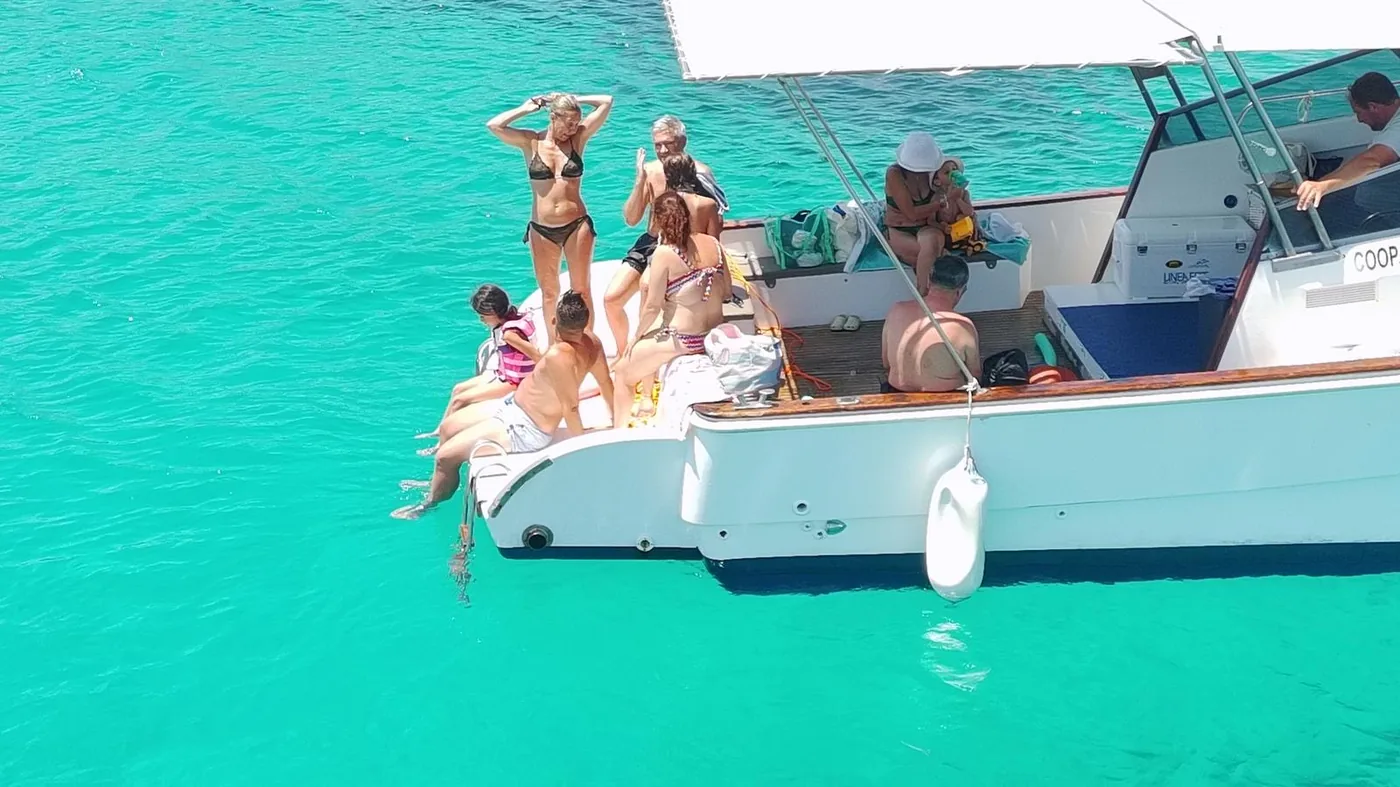 Gruppo di ospiti sul ponte della barca nelle acque cristalline di Favignana